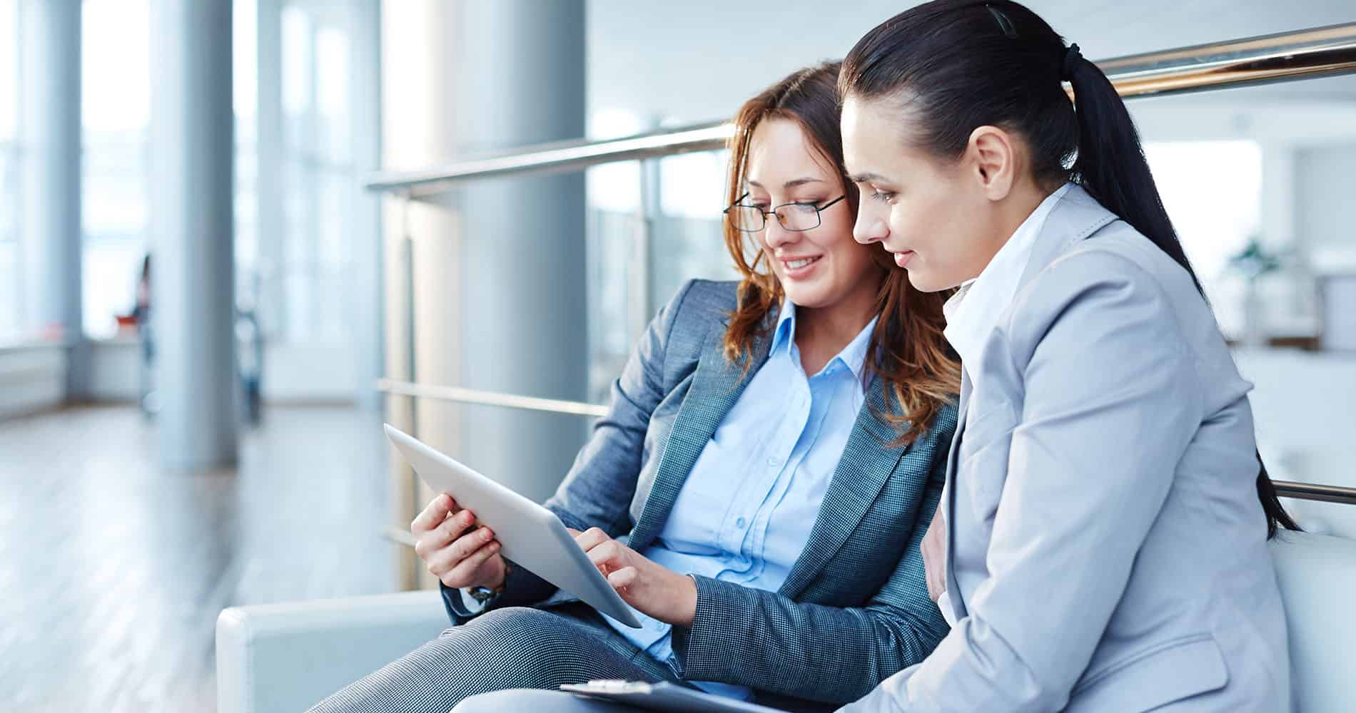 Two businesswomen watching something on touchpad